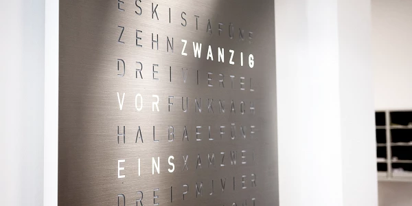 Moderne Uhr bestehend aus Worten aus Edelstahl