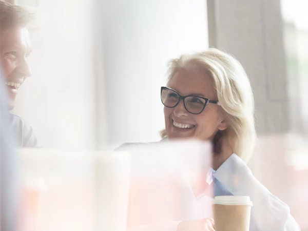 Frau und Mann lachen zusammen und sitzen im Büro, freundlich helle Umgebung