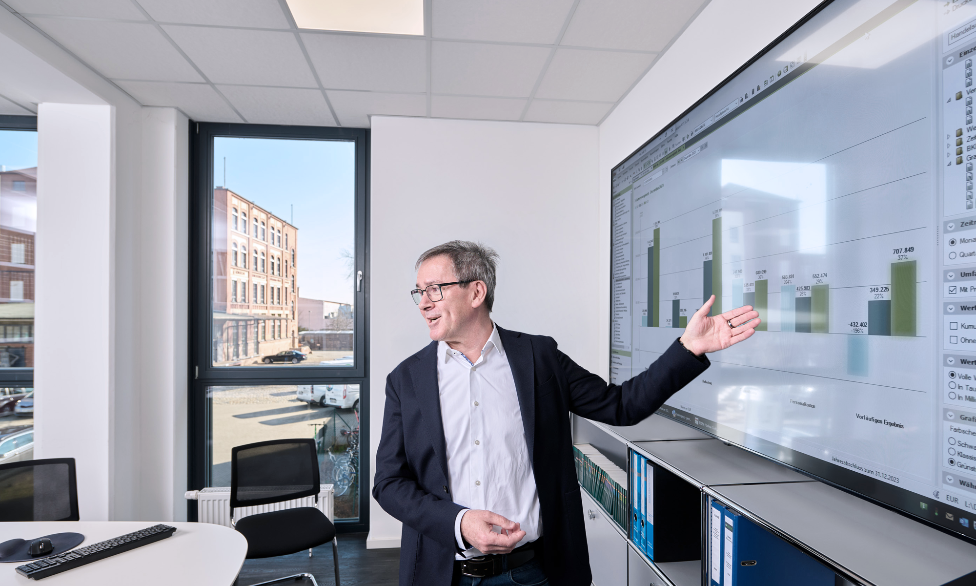 Mann präsentiert Diagramme auf großem Bildschirm in modernem Besprechungsraum