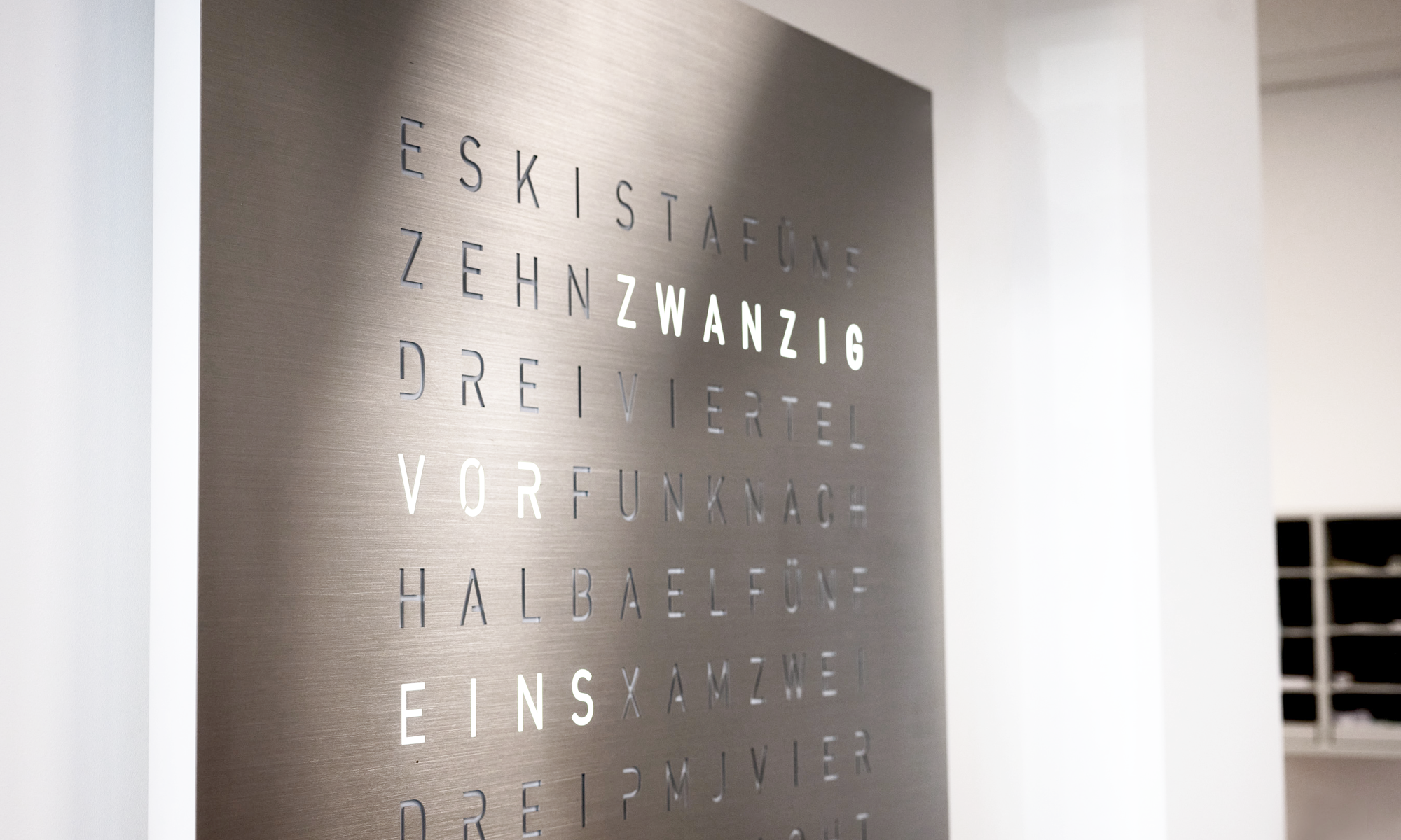 Moderne Uhr bestehend aus Worten aus Edelstahl