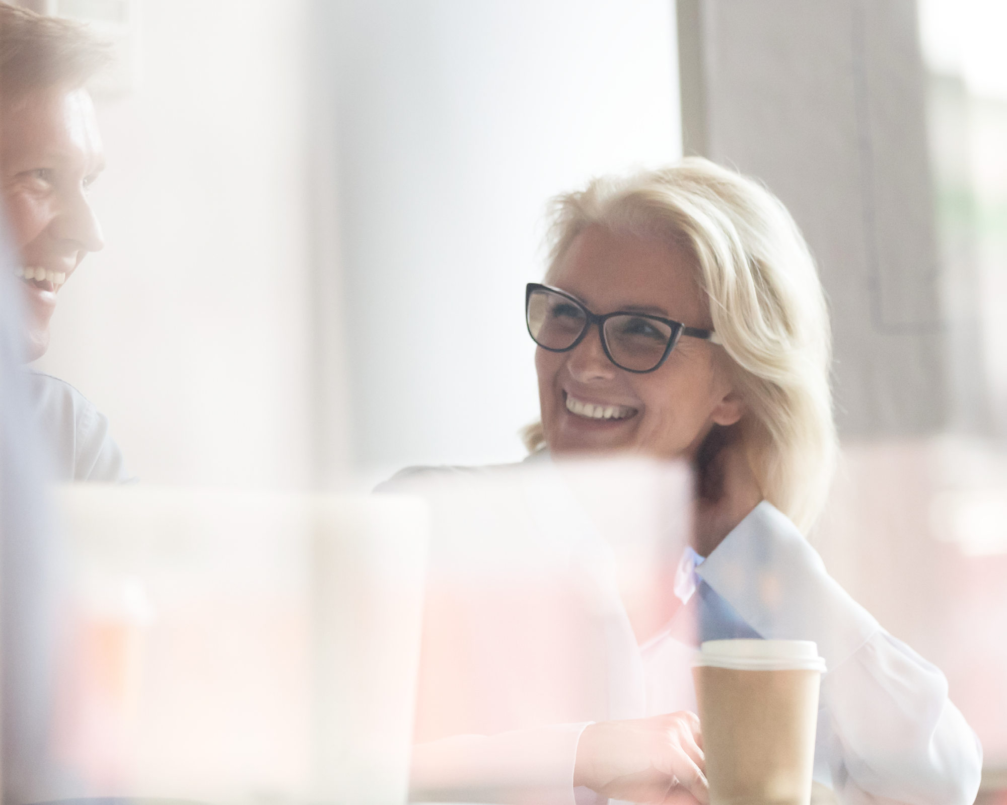 Frau und Mann lachen zusammen und sitzen im Büro, freundlich helle Umgebung